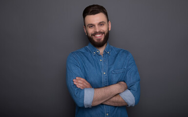 Close up photo of excited happy young modern bearded hipster man in jeans wear isolated on the gray background