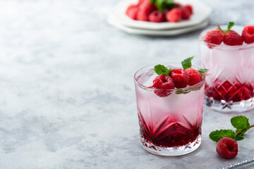 Raspberry cold drink cocktail with mint leaf and ice cubes. Summer fresh beverage in glass. Copy space.