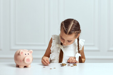 Little child girl with piggy bank at home