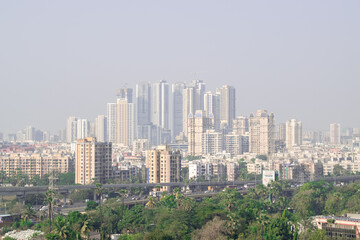 Fototapeta na wymiar Rural to urban development of mumbai with trees and skyscrapers in background