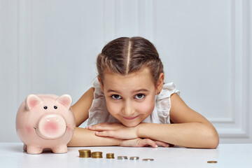Little child girl with piggy bank at home