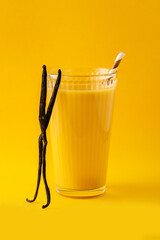 Delicious vanilla milkshake in glass on yellow background