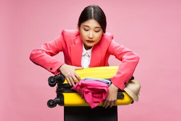 woman collecting clothes in a suitcase travel plane model pink jacket