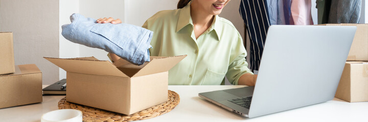 Asian business owner working at home with packing box of her online store prepare to deliver...