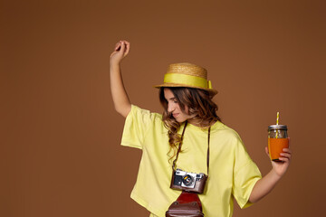 attractive girl in hat with orange juice and retro camera