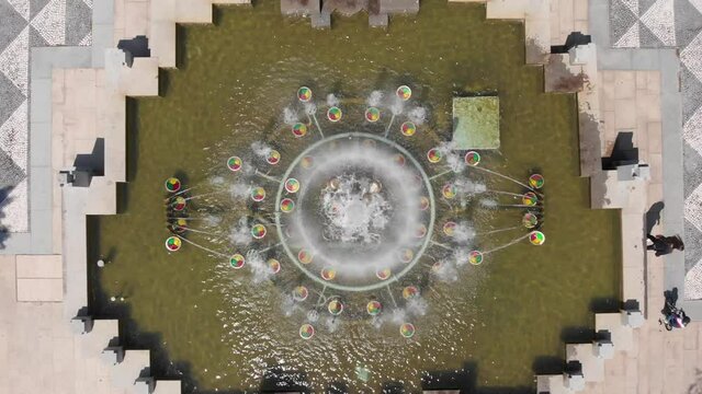 DRONE AERIAL FOOTAGE: Colorful fountain at the 25th of April Square (Portuguese: Praca 25 de Abril), Portugal.