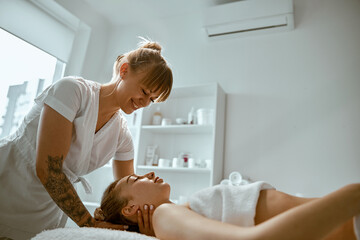 Obraz na płótnie Canvas Adult female specialist is doing neck massage to a young natural beautyful female client