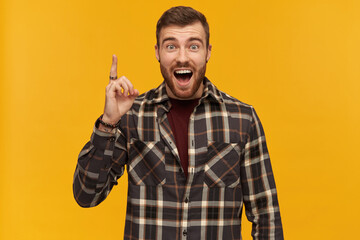 Happy exited young bearded man in plaid shirt shouting pointing up by finger and having an idea...