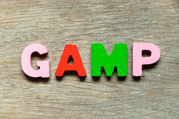 Fototapeta premium Color alphabet letter in word GAMP (Abbreviation of Good Automated Manufacturing Practice) on wood background