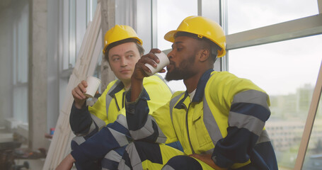 Diverse builders resting and drinking coffee at construction site