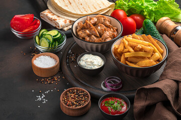 Ingredients for homemade shawarma, burritos, gyros on a brown background. Fried meat, French fries, vegetables and pita bread. Lunch.