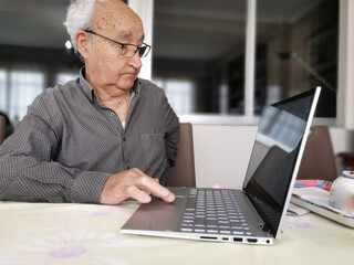 Serious older man using laptop close up, looking at screen, watching video or surfing internet, focused mature male using online clinic service or searching insurance information, medical app