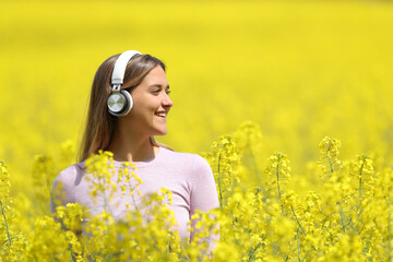 Happy woman listening to music contemplating in a yellow field