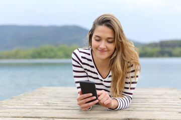 Fototapeta na wymiar Woman using smartphone in a lake pier