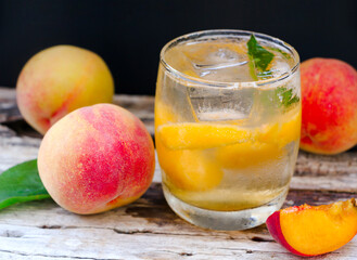 Delicious peach  with soda water on old white wooden table and dark background.