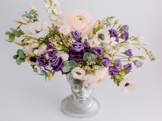Woman face in the shape of a vase for flowers with Anemone eustoma ranunculus.
