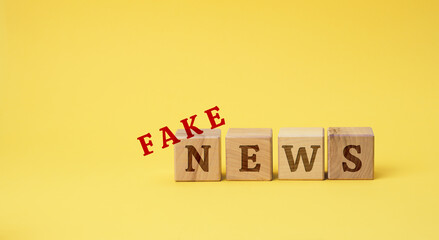 wooden cubes with the inscription false news on a yellow background. The concept of information hygiene, propaganda, debunking of myths and false information