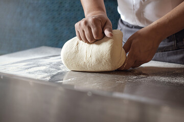 Deeg maken voor brood door mannelijke handen in de keuken van het restaurant. Koken concept.