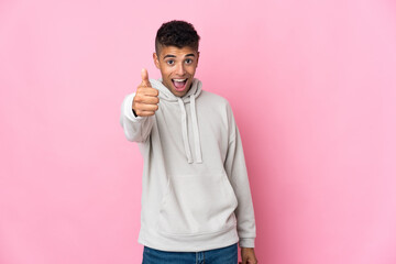 Young Brazilian man isolated on pink background with thumbs up because something good has happened