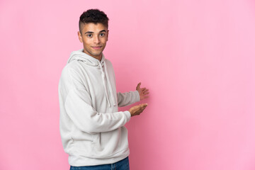 Young Brazilian man isolated on pink background extending hands to the side for inviting to come