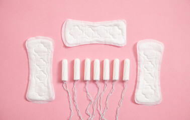 Menstrual pad and tampons on a pink background.