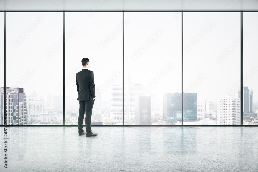 Aufkleber vision concept with businessman looking through big window on city skyscrapers in empty office hall 