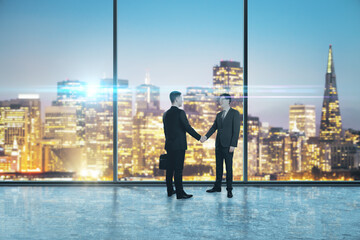 Fototapeta na wymiar Two businessmen shaking hands in an empty big office room with big windows and night city view, reaching an agreement. Communication and cooperation concept