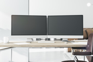 Stylish workspace with two black computer monitors with copyspace for your logo on wooden table in light sunny room. 3D rendering, mockup