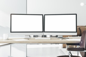 Blank white computer monitors on light wooden table with keyboard and brown leather chair near. 3D...