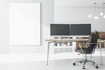 Blank white poster on light wall in stylish room near work place with modern computer monitors on wooden table and brown chair. 3D rendering, mock up