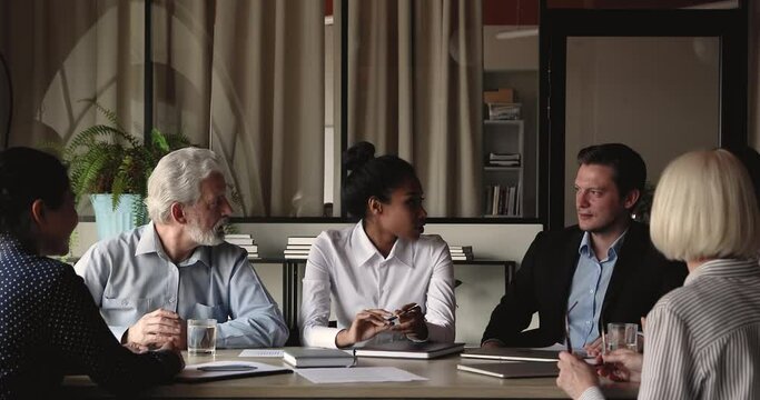 Interested diverse old young business people listening to confident skilled african american female manager, sharing project ideas at office meeting, briefing talking discussing problems solution.