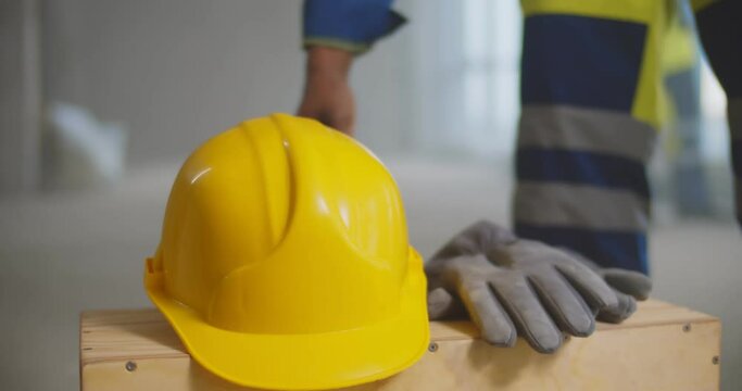 Close up of builder putting safety hardhat and gloves on wooden box
