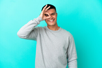 Young handsome man over isolated blue background showing ok sign with fingers