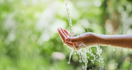 water pouring flow on woman hand  on nature background - Powered by Adobe