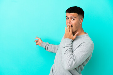 Young handsome man over isolated blue background with surprise expression while pointing side