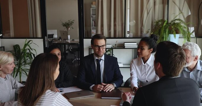 Confident 30s businessman in formal wear finishing presenting project ideas to motivated multiracial diverse old young colleagues at briefing meeting, shaking hands making deal with group of partners.