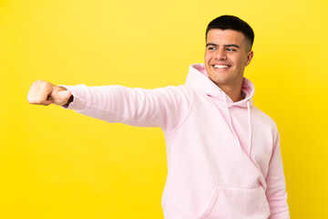 Young handsome man over isolated yellow background giving a thumbs up gesture