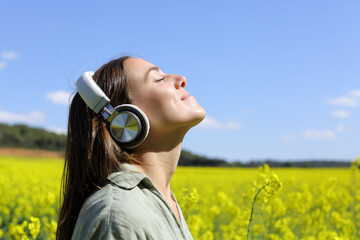 Happy woman meditating with headphones in a field