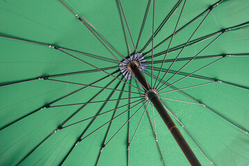 Low angle of the old and rusty green canvas parasol umbrella handle and frame