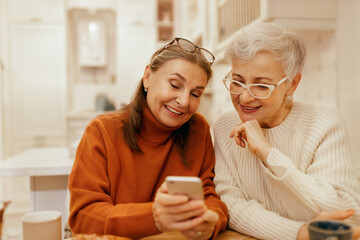 Technology, communication and networking. Modern elderly woman with gray hair holding cell phone,...