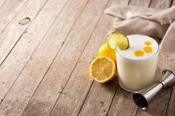 Pisco sour cocktail on wooden table. Traditional peruvian cocktail.Copy space