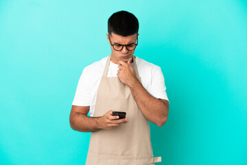 Restaurant waiter man over isolated blue background thinking and sending a message