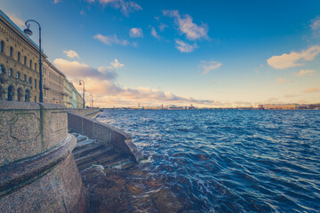 Granite quay of St. Petersburg passing along the Neva River on a winter morning. View from the level of descent to water