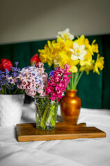 Bouquets of spring flowers yellow narcissus, tulips, hyacinth arranged in vases placed on the table.
