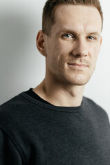Fototapeta premium Close-up portrait of a young red-haired guy who is looking at the camera against the background of a gray wall. Place for your text.
