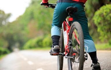 Woman riding a bike on tropical park trail in spring