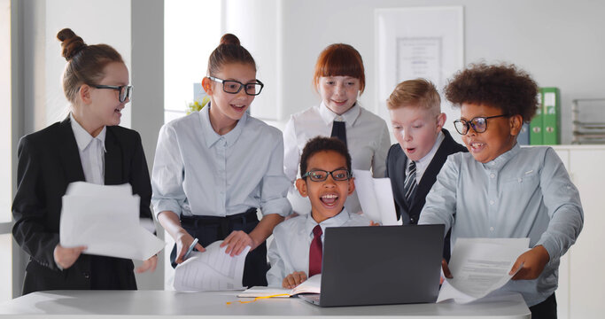 Cute multiracial children working together as team hugging and celebrating success