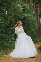 Fototapeta premium Happy bride in the forest. Full-length portrait. Wedding in the woods. The bride is dancing in the forest.