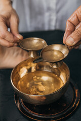 Close-up of two hands lifting oil. Oil applicator for relaxing massage. Gold body treatment