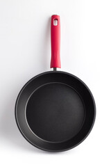 Clean black frying pan with a red handle on a white background. Isolated object
